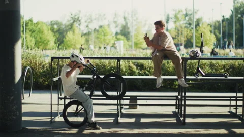 Boy Filming Friend Doing BMX Bicycle Stunt on Smartphone Video stock 346146794