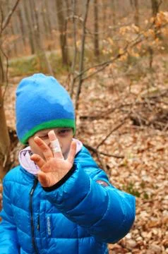 Boy finds a cache during geocaching and shows his injured finger with plaster Stock Photos