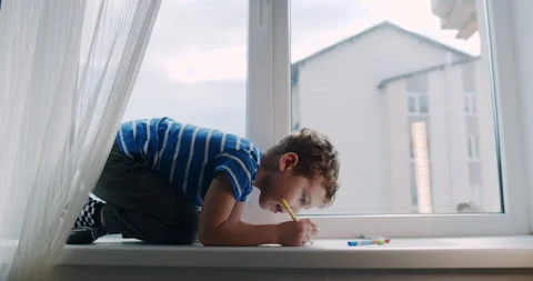 A boy finds joy in art on a window sill, capturing his imagination Video stock 307300187