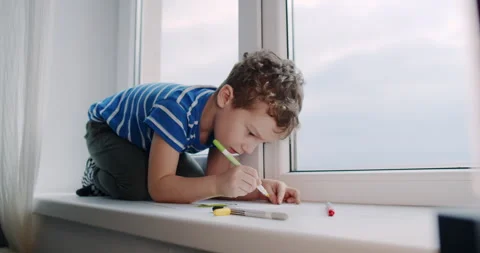 A boy finds peace on a window sill, expressing creativity through art Stock Footage 307305514