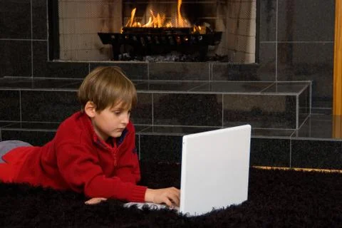 Boy at fireplace on computer. 写真素材