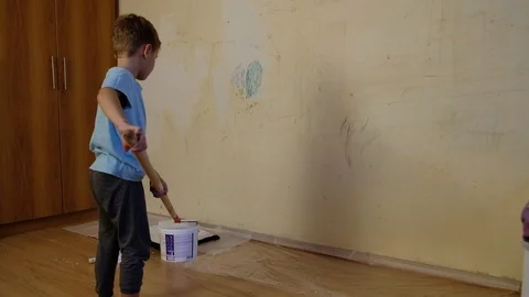 A boy of five years paints a wall with drawings of white paint. Stock Footage 118887670