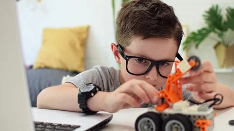 Boy fixes sensor chip at robot car. Child nerd learns coding. Robotics, STEM. Stock Footage 196792929