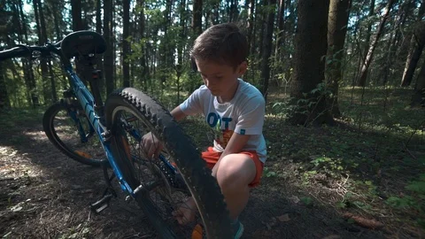 The boy is fixing a bicycle in the forest Stock Footage 90429291