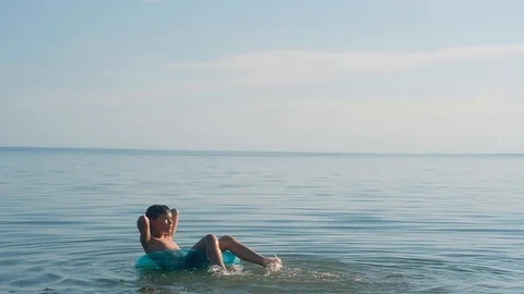 Boy floating on the water on a blue inflatable circle Stock Footage 114507518
