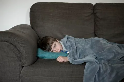 Boy with flu, lying on the sofa Stock Photos