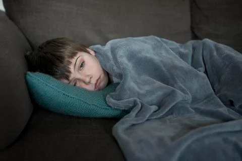 Boy with flu, lying on the sofa Stock Photos