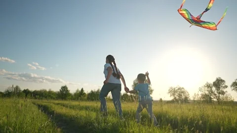 Boy fly kite while girl runs on field. Summer sky above green field. Child holds Stock Footage 320114392