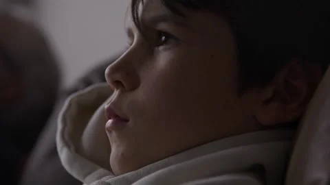 Boy focused playing video games as parent sits down besides him - close up .. Stock Footage 316199285