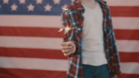 Boy in front of american flag holding sparkler in hand. shot in slow motion Stock Footage 75779671