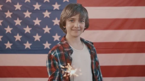 Boy in front of american flag holding sparkler in hand. shot in slow motion Stock Footage 75779689