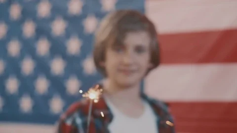 Boy in front of american flag holding sparkler in hand. shot in slow motion Stock Footage 75780691