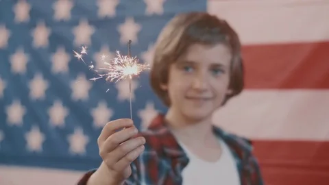 Boy in front of american flag holding sparkler in hand. shot in slow motion Stock Footage 75780763