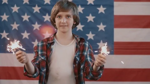 Boy in front of american flag holding sparklers in hands. shot in slow motion Stock Footage 75784096