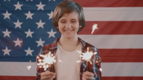 Boy in front of american flag holding sparklers in hands. shot in slow motion Stock Footage 75784292