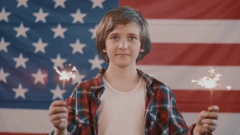 Boy in front of american flag holding sparklers in hands. shot in slow motion Stock Footage 75784508