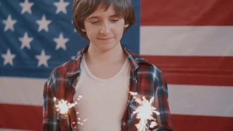 Boy in front of american flag holding sparklers in hands. shot in slow motion Stock Footage 75784905