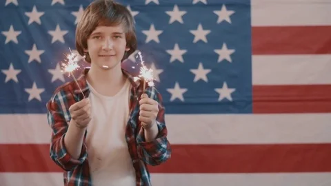 Boy in front of american flag holding sparklers in hands. shot in slow motion Stock Footage 75785079