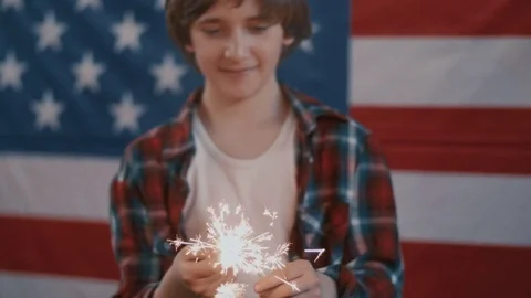 Boy in front of american flag holding sparklers in hands. shot in slow motion Stock Footage 75785103
