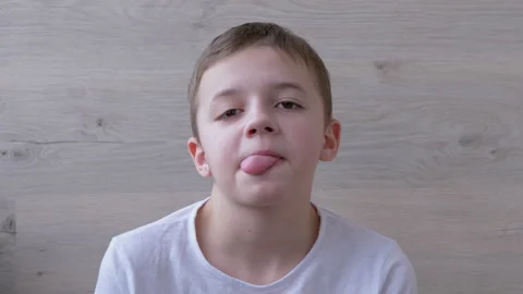 Boy with Full Lips, Long Eyelashes Makes Grimaces, Sticks Out Tongue. Humor. 4K Stock Footage 150976061