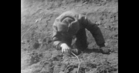 Boy in a fur hat is trying to climb out of a ravine. Difficult to climb up the Vídeos de archivo 260540785