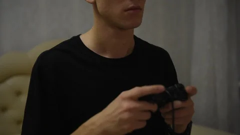 Boy gamer plays with a gamepad while looking at the screen in front of him Stock Footage 121166245