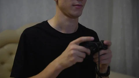 Boy gamer plays with a gamepad while looking at the screen in front of him Stock Footage 121166279