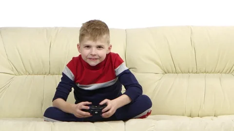 Boy with games console playing video game on the sofa Stock Footage 75918970