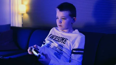Boy gets a big shock as he plays video game and looks at the screen Stock Footage 98849752