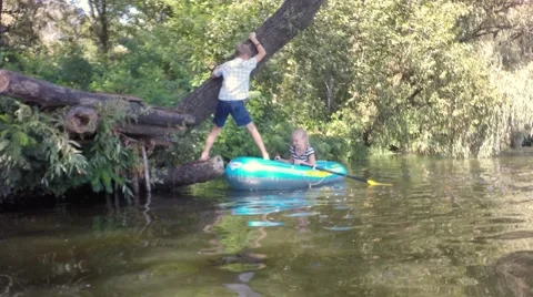 The boy gets into a boat. Summer river. Children laugh. Video stock 66774051