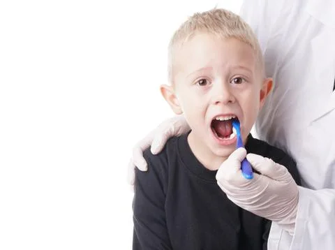 Boy gets help by the Dentist to brush his teeth Stock Photos