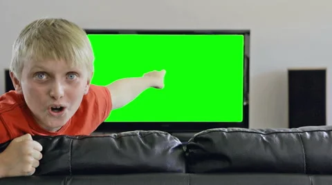 Boy gets hugely excited and enthusiastic, smiles, points at green TV Stock Footage