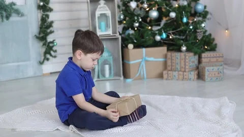 A boy with a gift under the Christmas tree. Festive mood. A gift for the new Stock Footage 165238007