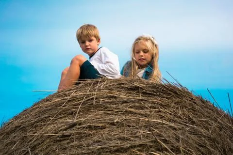 Boy with a girl sitting on  haystack  the background of the sky Stock Photos