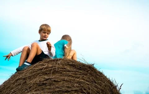 Boy with a girl sitting on  haystack  the background of the sky Stock Photos