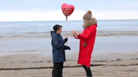 Boy gives mom large red balloon in the shape of heart Stock Footage 145979725