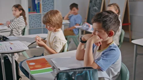 Boy giving note classmate at cozy class room. Funny pupils kids communicating Stock Footage 279576021