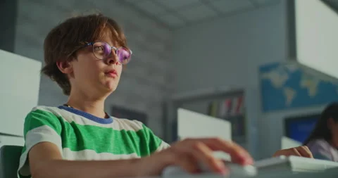 Boy With Glasses Concentrating on Desktop Computer in School Stock Footage 318072533