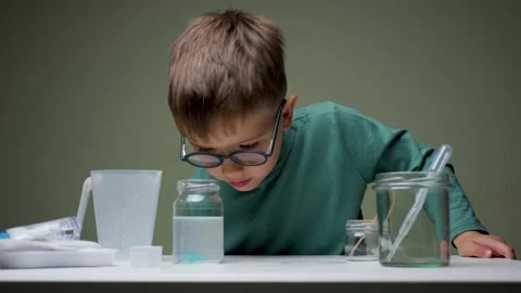 Boy in glasses does chemical experiment with pipette and liquid indoor. Studying Stock Footage 139850293