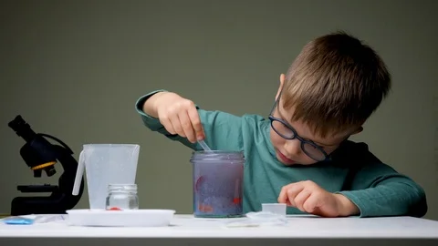 Boy in glasses doing experiment. Young scientist mixing up licquid for Stock Footage 119361461