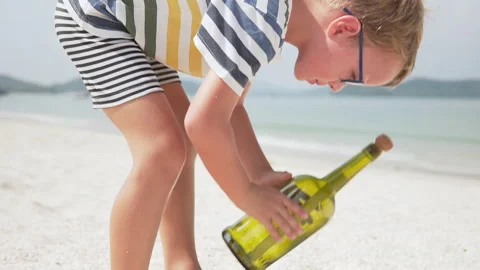 Boy in glasses is founding a message in a bottle Stock Footage 262837636