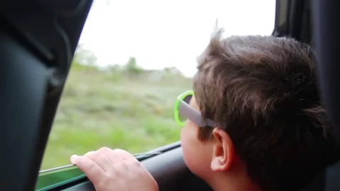 The boy in glasses looks into the open window of the car Stock Footage 76433370