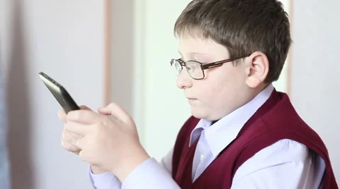 Boy with glasses playing the tablet at school Stock Footage 58866904