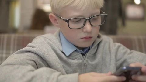 A boy with glasses plays chess on a mobile phone Stock Footage 116464560