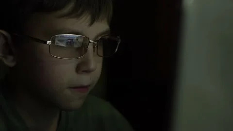 A boy with glasses plays a game on a computer. Stock Footage 145483479
