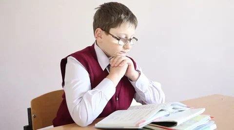 Boy with glasses reading a book and rubs his eyes hands Stock Footage 58867067