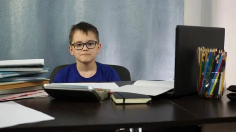 A boy with glasses sitting at the table shows his fist. he is so angry about the Stock Footage 144935099