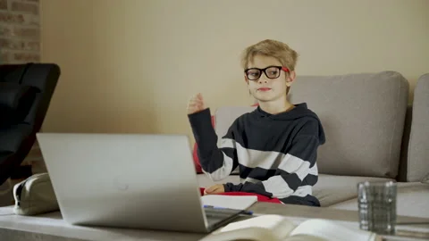 Boy with glasses is thinking sitting on the sofa in front of laptop, Stock Footage 220292856