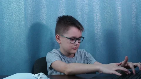 A boy with glasses types on a computer then turns around and gives a thumbs up Stock Footage 144467879