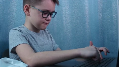 A boy with glasses is typing on a laptop. study in quarantine at home Stock Footage 144683323